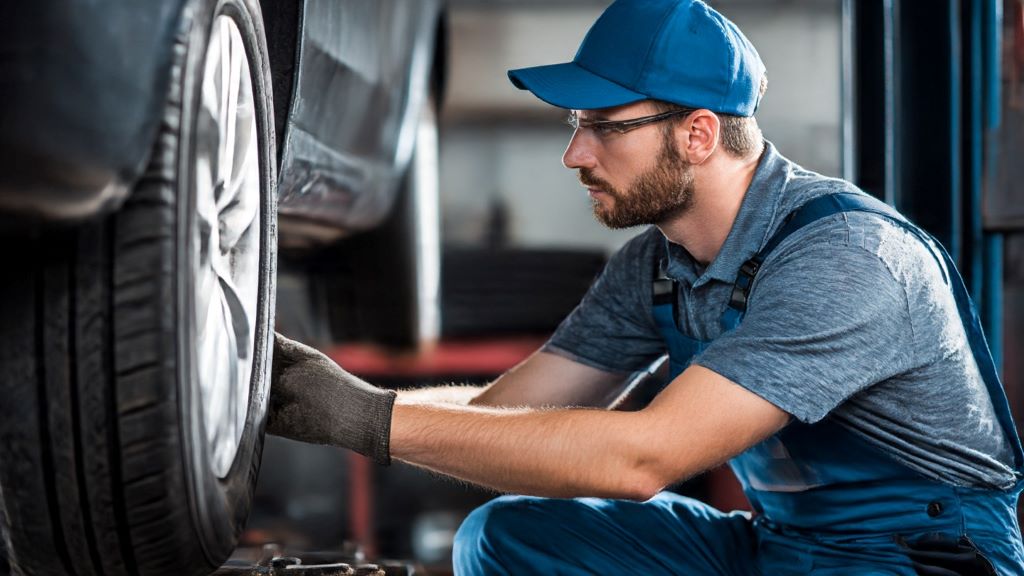 Mechanic inspecting worn tire tread causing vibration and humming noise